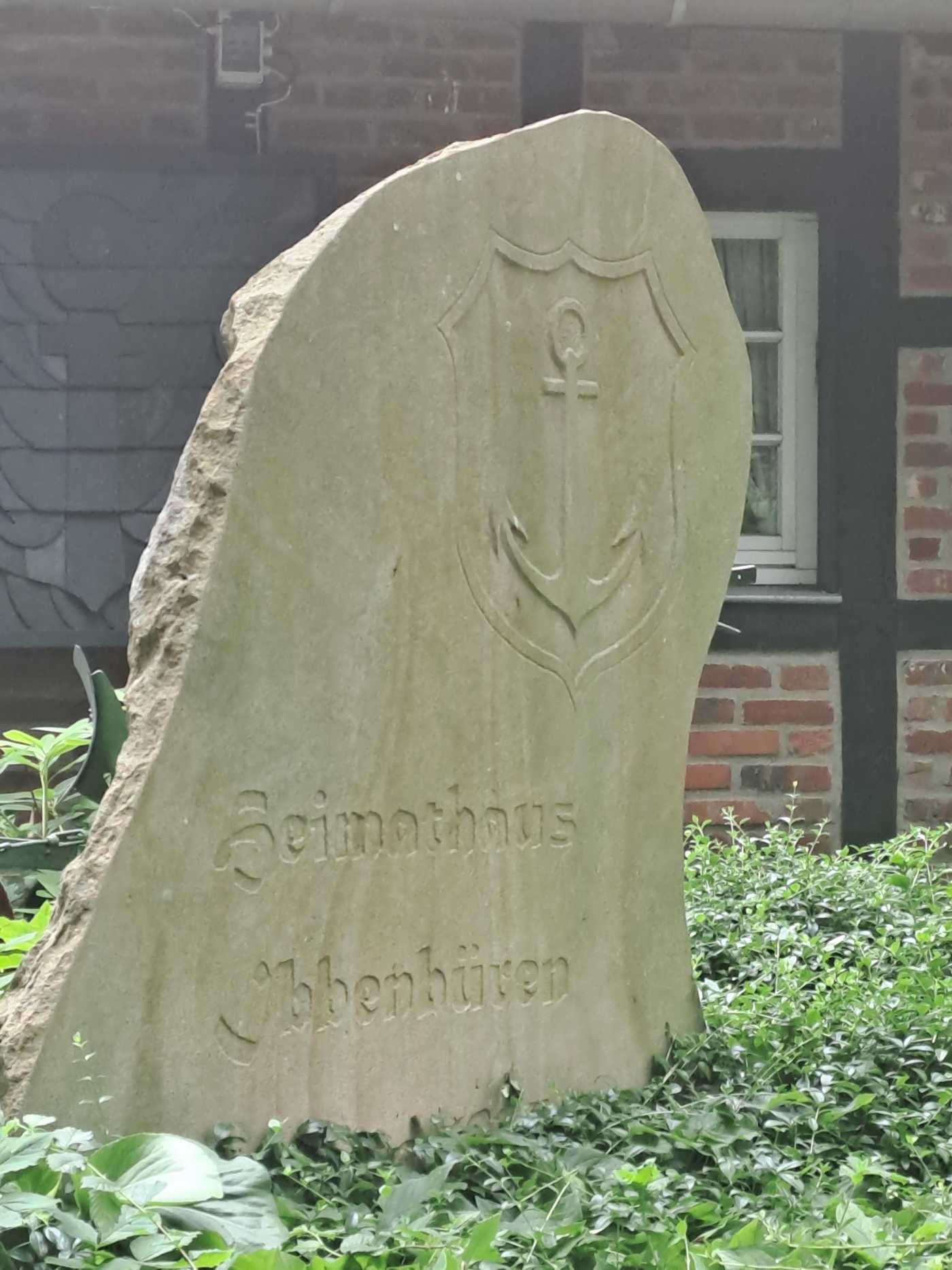 Sandstein mit dem Stadtwappen von Ibbenbüren im Beet vor dem Heimathaus