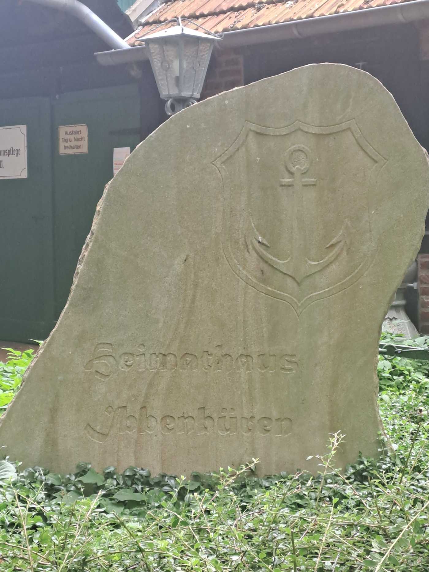 Sandstein mit dem Stadtwappen von Ibbenbüren im Beet vor dem Heimathaus